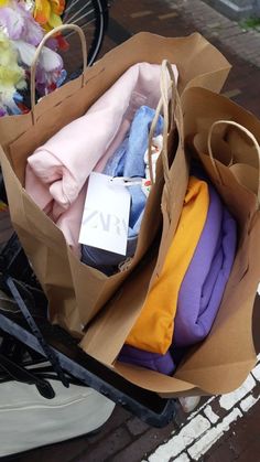 a brown paper bag filled with clothes on top of a bike seat next to flowers