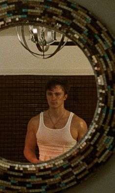 a man is standing in front of a mirror with beads on it and looking at his reflection