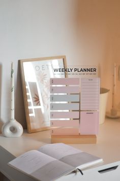 an open planner sitting on top of a desk next to a pen and paper holder