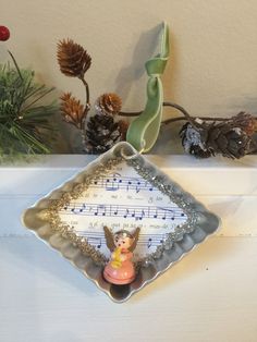 an ornament with musical notes on it and pine cones in the back ground