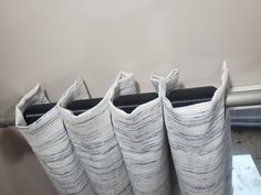 three black and white vases sitting on top of a table next to a wall