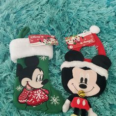 two mickey and minnie mouse christmas stocking holders on a blue fuzzy carpet with snowflakes