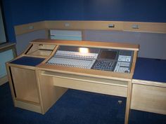 an electronic mixing desk in a room with blue carpeting and wooden cabinets on either side