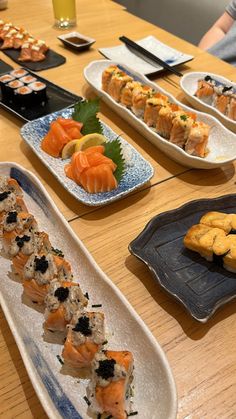 sushi platters are lined up on a table with plates and utensils