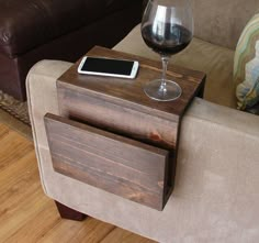 a glass of wine sitting on top of a wooden table next to a couch with a cell phone