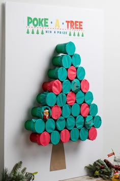 a christmas tree made out of toilet paper rolls on top of a white board with green and red circles