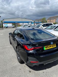 the rear end of a black car parked in a parking lot next to other cars