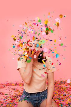 a woman sitting on the ground surrounded by confetti