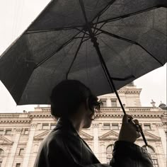 a person holding an umbrella in front of a building