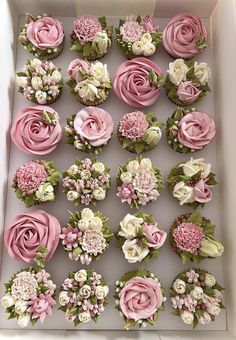 cupcakes decorated with pink and white flowers in a box