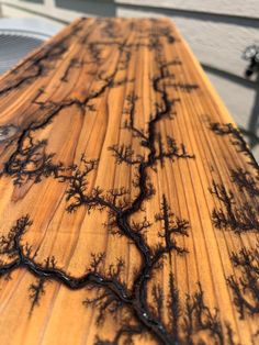 a close up of a wooden table with black paint on the top and tree branches painted on it