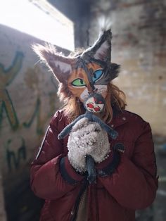 a person wearing a cat mask and holding a stuffed animal