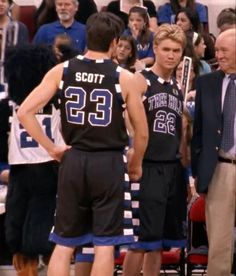 two basketball players standing next to each other in front of an audience at a game