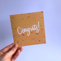 someone holding up a congrats card with confetti on the front and bottom