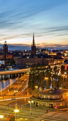 an aerial view of a city at night with lights and traffic on the streets in the foreground