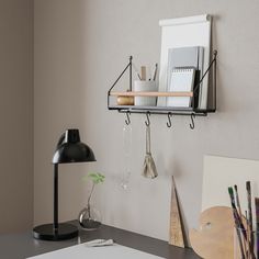 a desk with a lamp, pictures and other items hanging on the wall above it