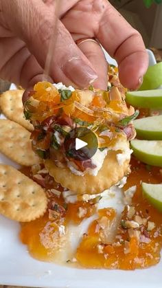 a person is picking up some food from a plate with crackers and apple slices