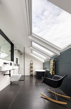 a modern bathroom with skylights above the sinks and bathtubs, along with a rocking chair