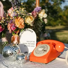 an orange phone sitting on top of a table next to flowers and disco ball decorations