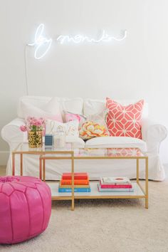 a white couch sitting next to a pink ottoman