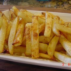 french fries are sitting on a plate with seasoning sprinkled over them, ready to be eaten