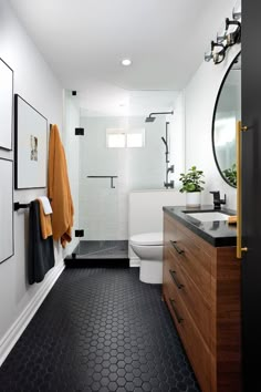 a bathroom with black and white tile flooring, wooden cabinetry, and toilet