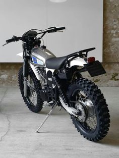 a dirt bike parked in front of a white wall and cement flooring with an open door