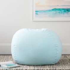 a light blue bean bag sitting on top of a rug next to a white wall