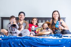 a group of people sitting on top of a bed with books and drinks in front of them