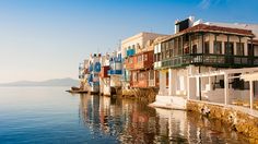 a row of buildings next to the water with text that reads mykonos greek guide