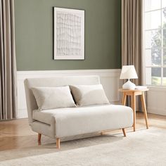 a living room with green walls and a white couch next to a lamp on a table