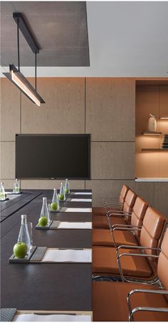 an empty conference room with long tables and leather chairs in front of a flat screen tv