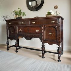 an old fashioned wooden desk in a room with a mirror and potted plant on top