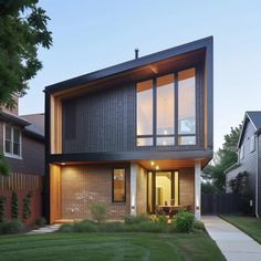 a modern house with large windows and grass in the front yard