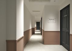 an empty hallway with two black doors leading to another room and a sign on the wall