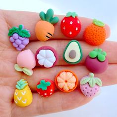 a hand holding a small assortment of fruit and vegetable magnets on it's fingers