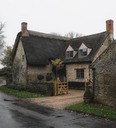 an old stone house with a thatched roof and wooden gate in front of it