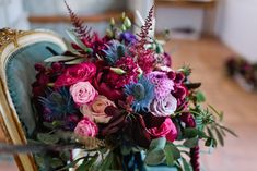 a bouquet of flowers sitting on top of a blue chair in front of a mirror