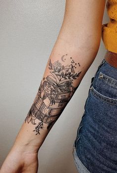 a woman's arm with a tattoo on it that has books and flowers on it