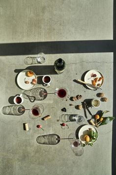 an overhead view of food and drinks on a concrete table with shadow from the sun