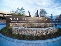 the natick collection sign is in front of a stone wall and blue brick walkway