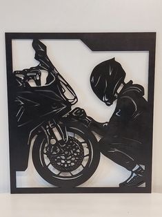 a metal cutout of a motorcyclist on a motorcycle in a frame