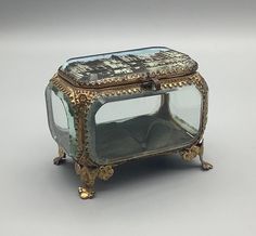 an antique glass and metal box with writing on the front, sitting on a white surface