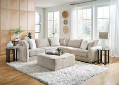 a living room filled with lots of furniture next to a large white rug on top of a hard wood floor