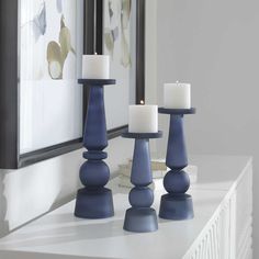 three candles sitting on top of a white shelf