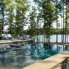 an outdoor swimming pool surrounded by trees and water with benches on the side overlooking it