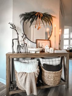 a wooden table topped with two baskets filled with pillows and blankets next to a mirror