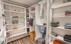 a walk in closet with white shelving and wooden flooring