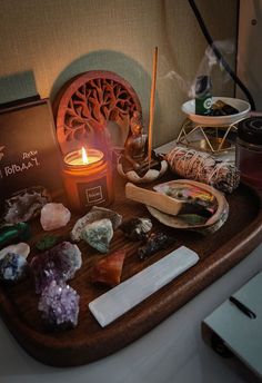 an assortment of rocks and candles on a tray with a candle in the middle next to it