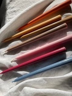 five different colored pens lined up on a white cloth